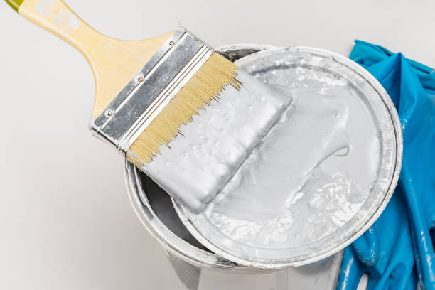 istock Plastic container with paint, paintbrush and blue latex gloves. Construction and renovation concept. 1300111045