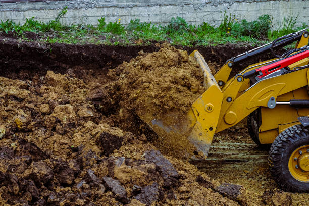 istock Backhoe loader moves clay soil in the excavation to the dump. Construction site planning and cutting the ground with a bulldozer. 1300111699
