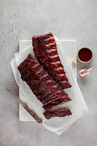 Full rack of grilled barbecue ribs with barbecue sauce on white background