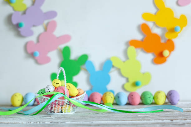 istock Colorful Easter eggs in basket and handmade bunny easter garland on beige background. 1300113938