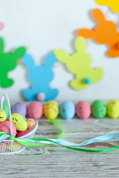 istock Colorful Easter eggs in basket and handmade bunny easter garland on beige background. 1300113942