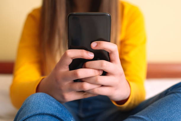 istock Young woman with mobile phone lying in bed 1300115510