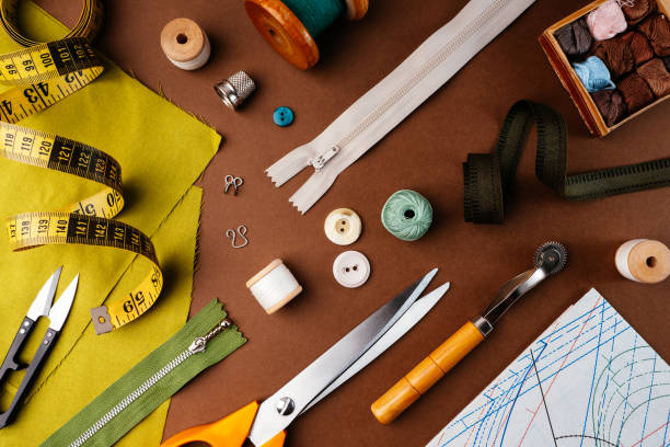 istock Flat lay composition of sewing accessories, scissors, patterns, fabrics on a brown background, top view. The desktop of a fashion designer, tailor in an atelier. Vintage style sewing concept 1300116426