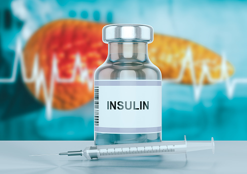 Vial de insulina y una jeringa en el banco del hospital con páncreas en segundo plano photo