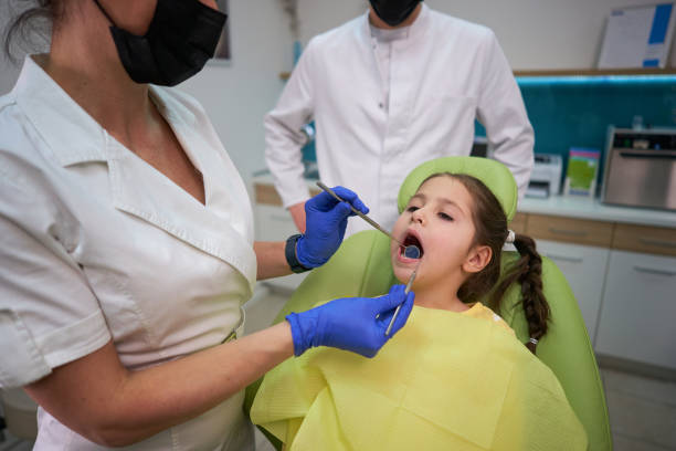 istock Expertised female dentist using dental probe and angled mirror while doing tooth status on a female child 1300123686