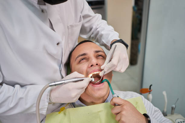 istock Male patient holding a suction tube, while dentist using a dental drill to remoe tooth decay 1300124708