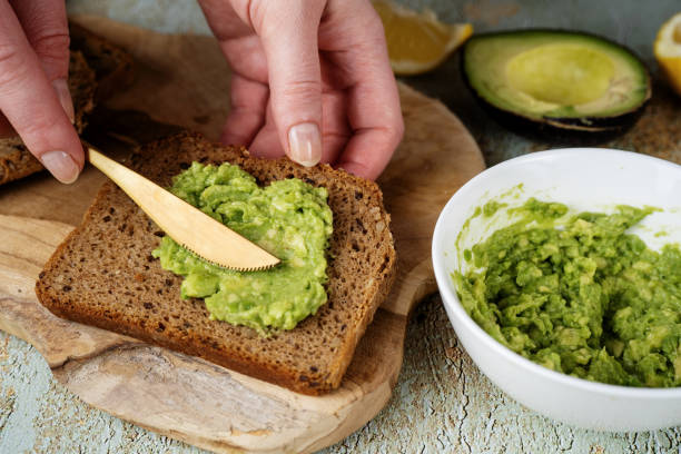 istock Spreading mashed avocado on healthy slice of bread 1300126254