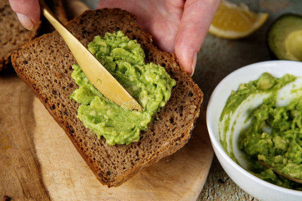istock Mashed avocado. Spreading minced avocado on healthy slice of bread 1300126275
