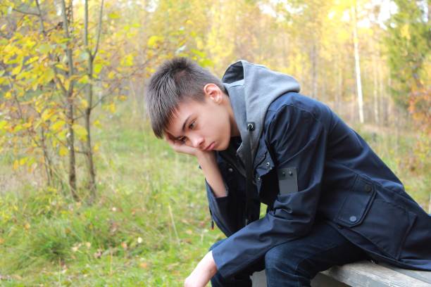 istock Sad teenage boy sitting on a bench alone 1300127003