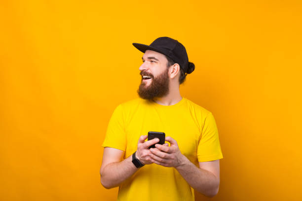 istock Portrait of handsome young man with beard holding smartphone and looking a side at copyspace 1300128762