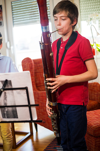 portrait of young Venezuelan musician of the Simon Bolivar symphony orchestra, at home holding a bassoon, standing on the balcony smiling and looking at the camera.