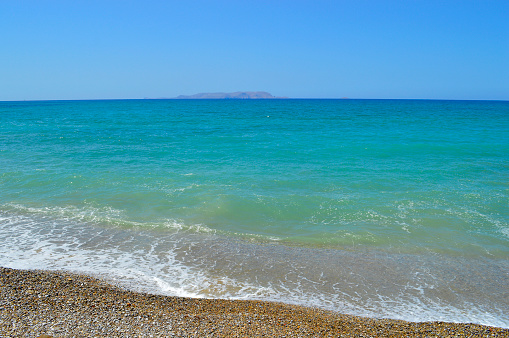 Kato Gouves pebble beach in Crete with the island of Dia on the horizon, one  of the Greek islands