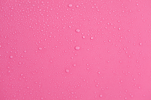 Full frame of the textures formed by the bubbles and drops of water. Drops of water spilled on a light pink surface