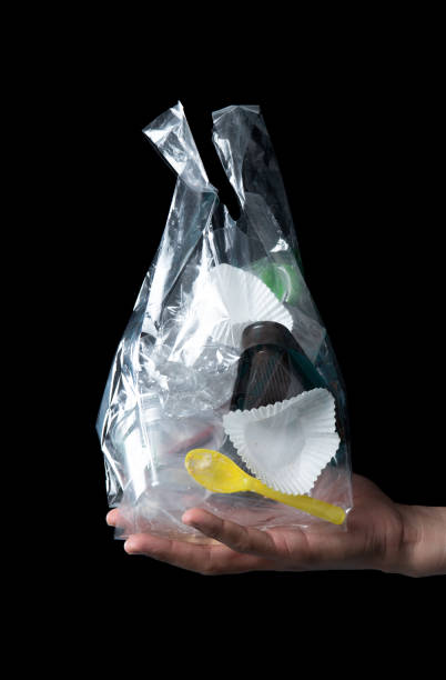 istock Hand holding clear plastic bag of garbage isolated on black background 1300134090