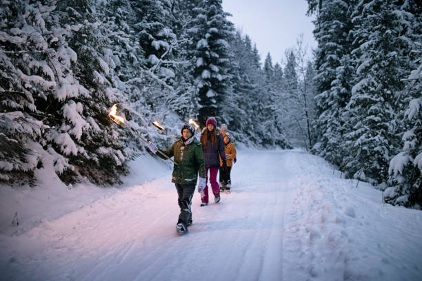 Family walking in winter forest with torches