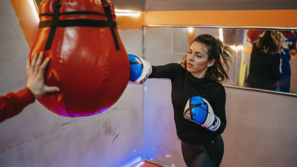 istock Female kick-boxer practicing with her coach in a gym 1300135975