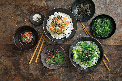 Tuna tataki. Rice bowl with salmon. Rice bowl with avocado. Flat lay top-down composition on dark background.