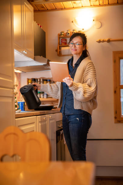 istock Woman holding tablet and pouring tea in the kitchen. 1300136844