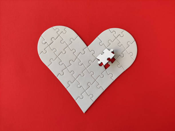 istock Heart shaped white jigsaw puzzle on red background, puzzle pieces completing the heart shape 1300136893