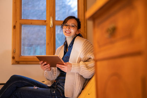 istock Woman looking at camera, holding rose gold digital tablet. 1300137104