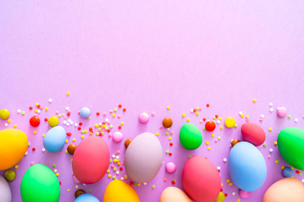istock Colorful Easter eggs with candies and sugar sprinkles on purple colored background. Copy space 1300137126