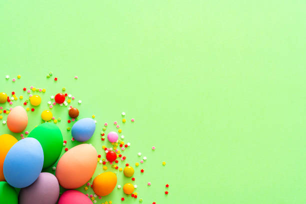 istock Colorful Easter eggs with candies and sugar sprinkles on green background. Copy space 1300137151