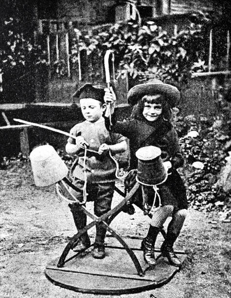 istock Children playing, boy and girl riding on an overturned table 1300137863