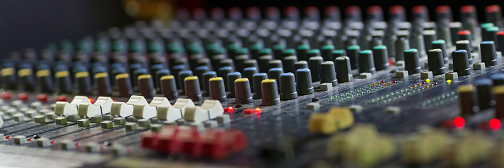 Control panel of a professional audio mixer for controlling live sound, indoor side view close-up