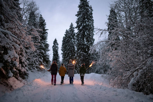 istock Family walking in winter forest with torches 1300141314