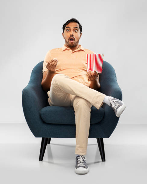 istock shocked indian man eating popcorn in chair 1300143031
