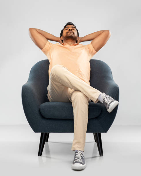 istock happy smiling young indian man sitting in chair 1300143041