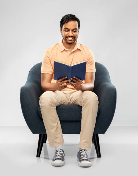 istock happy young indian man reading book in chair 1300143603