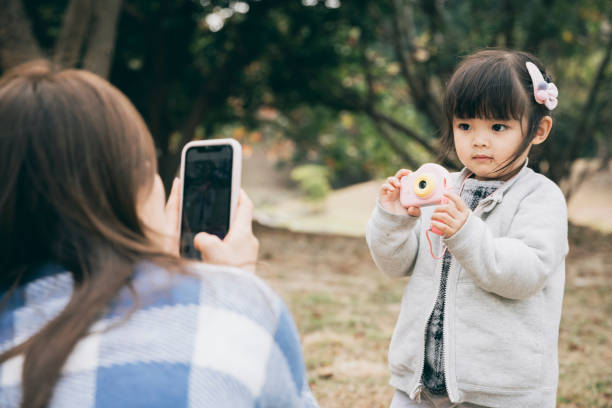 istock Mother and daughter using smartphone to take selfie 1300144871