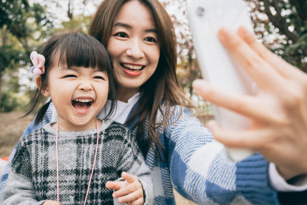 Mother and daughter using smartphone to take selfie