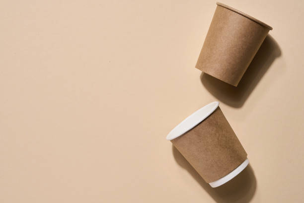 istock Renewable individual objects for home use, bamboo or paper straws, disposable cups and wooden coffee stirrers on beige with shade from leaves on beach. Zero waste. Pollution environment. Top view. 1300146493