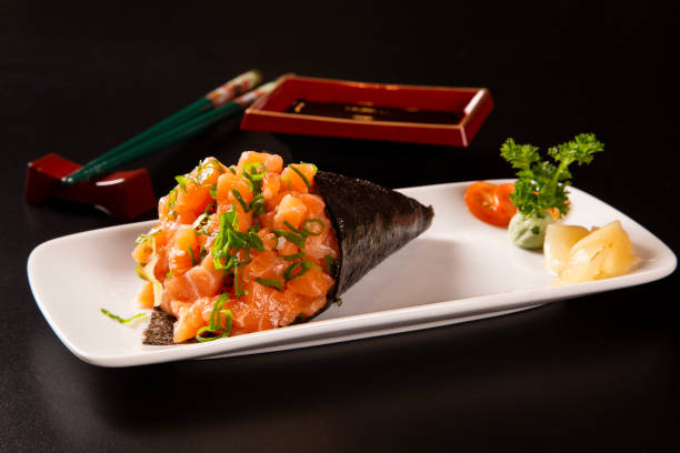 istock Salmon temaki sushi on white plate in black background. 1300149319