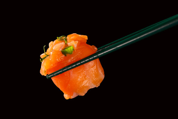 istock Hashi hold sushi and rolls isolated over black background 1300150706