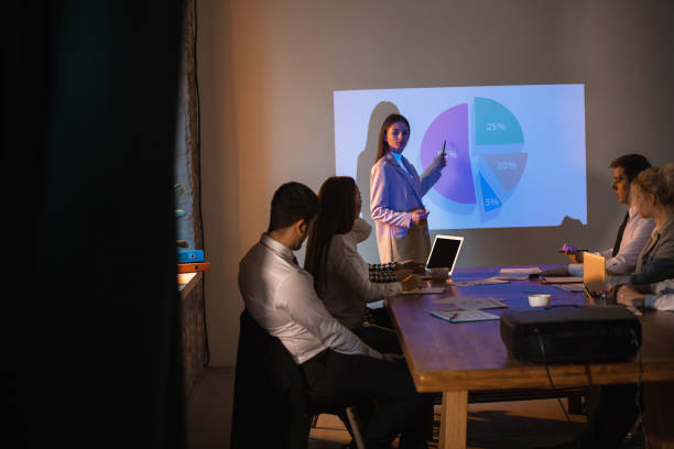 istock Female speaker giving presentation in hall at workshop. Audience or conference hall. Participants, co-workers listening at the table. 1300153554