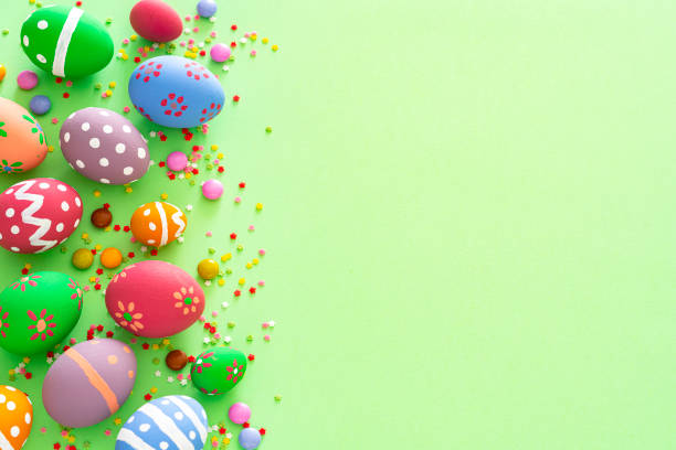 uova di pasqua colorate con caramelle e spruzzi di zucchero su sfondo verde. spazio di copia - decoration fun in a row vibrant color foto e immagini stock