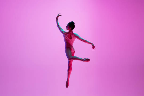 istock Young and graceful ballet dancer isolated on pink studio background in neon light. Art, motion, action, flexibility, inspiration concept. 1300154739