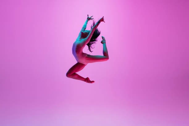 joven y elegante bailarina de ballet aislada sobre fondo de estudio rosa en luz de neón. arte, movimiento, acción, flexibilidad, concepto de inspiración. - baile ballet fotografías e imágenes de stock