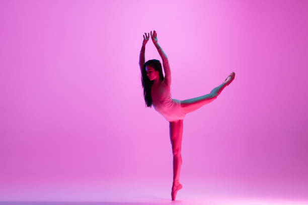 istock Young and graceful ballet dancer isolated on pink studio background in neon light. Art, motion, action, flexibility, inspiration concept. 1300154756