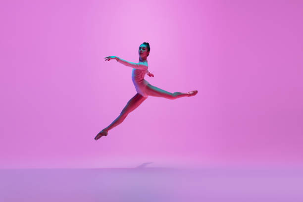 istock Young and graceful ballet dancer isolated on pink studio background in neon light. Art, motion, action, flexibility, inspiration concept. 1300154760