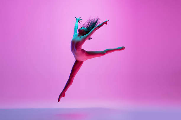 istock Young and graceful ballet dancer isolated on pink studio background in neon light. Art, motion, action, flexibility, inspiration concept. 1300154771