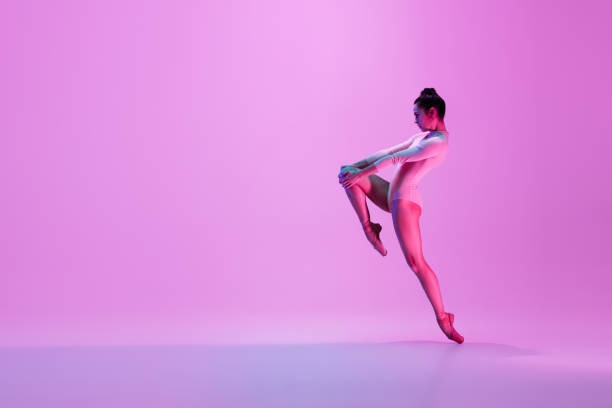 istock Young and graceful ballet dancer isolated on pink studio background in neon light. Art, motion, action, flexibility, inspiration concept. 1300154803