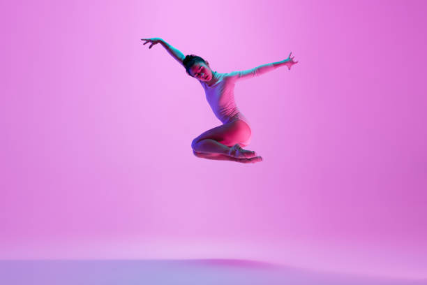 istock Young and graceful ballet dancer isolated on pink studio background in neon light. Art, motion, action, flexibility, inspiration concept. 1300154806