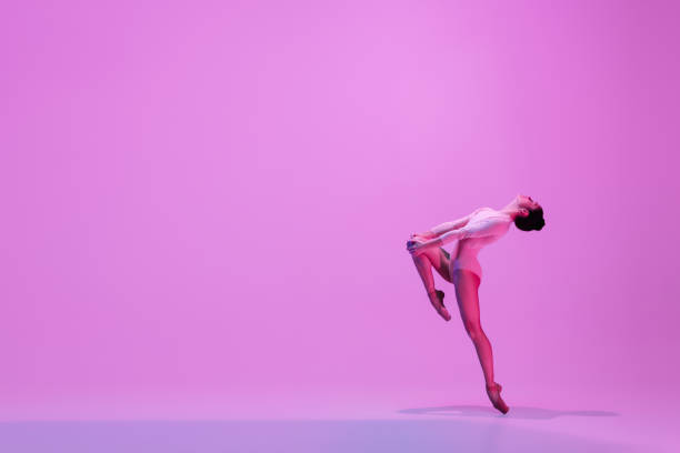 istock Young and graceful ballet dancer isolated on pink studio background in neon light. Art, motion, action, flexibility, inspiration concept. 1300154812