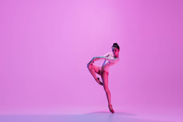 istock Young and graceful ballet dancer isolated on pink studio background in neon light. Art, motion, action, flexibility, inspiration concept. 1300154820