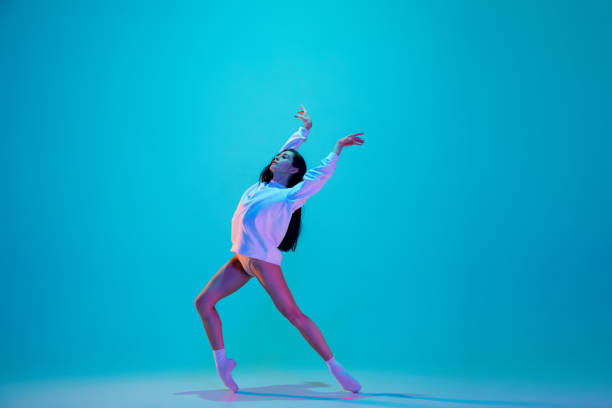 istock Young and graceful ballet dancer isolated on blue studio background in neon light. Art, motion, action, flexibility, inspiration concept. 1300154880