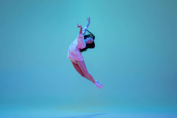 istock Young and graceful ballet dancer isolated on blue studio background in neon light. Art, motion, action, flexibility, inspiration concept. 1300154916